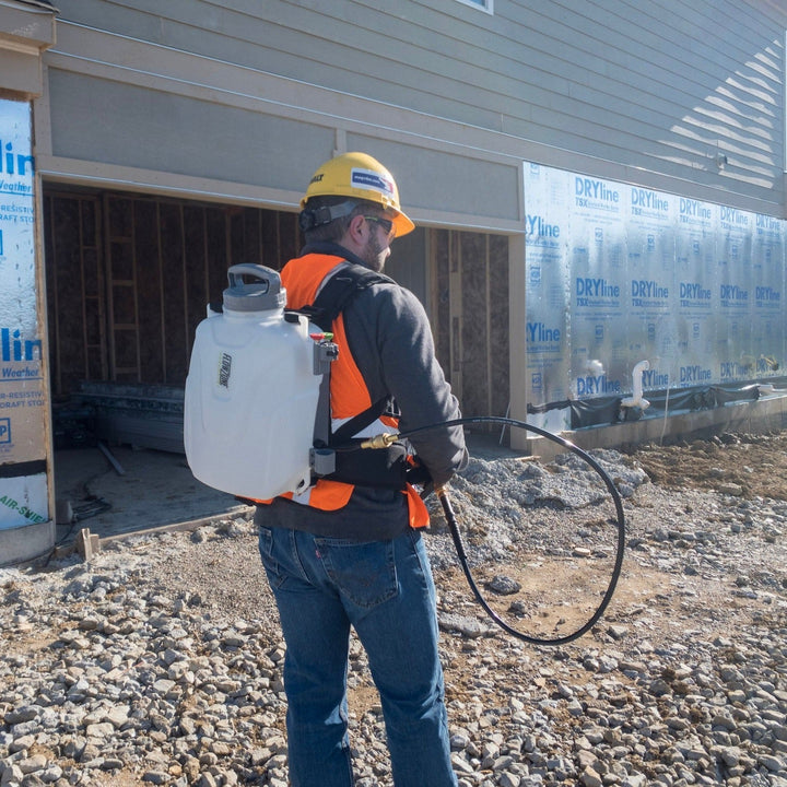 man with 2.5-gallon backpack sprayer standing in front of a house frame