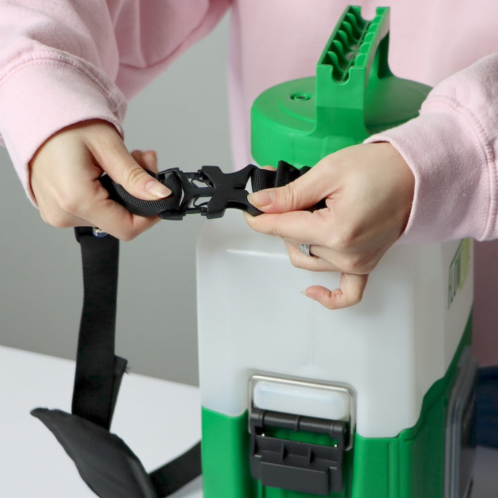Person attaching a black buckle strap to a flowzone storm 1 gallon sprayer