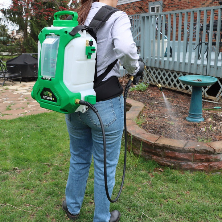 woman spraying edge of garden bed with backpack sprayer